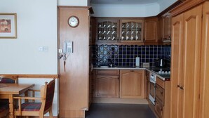 A compact kitchen with wooden cabinets, a built-in oven, and a tiled backsplash. - Otter Lodge 04 Loch Rannoch Highland Club (Pitlochry)