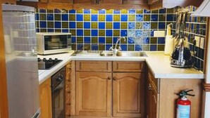 Eine Küche mit Holzausbau, einer gefliesten Spritzschutzwand, einem Edelstahlkühlschrank und einem Gasherd.