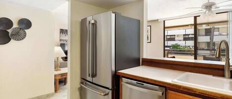 A modern kitchen with a stainless steel refrigerator, a dishwasher, and a wooden countertop.