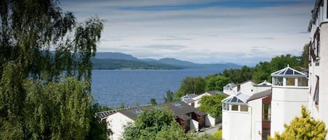 Eine Küstenwohngegend mit Häusern, einem See und Bergen im Hintergrund.