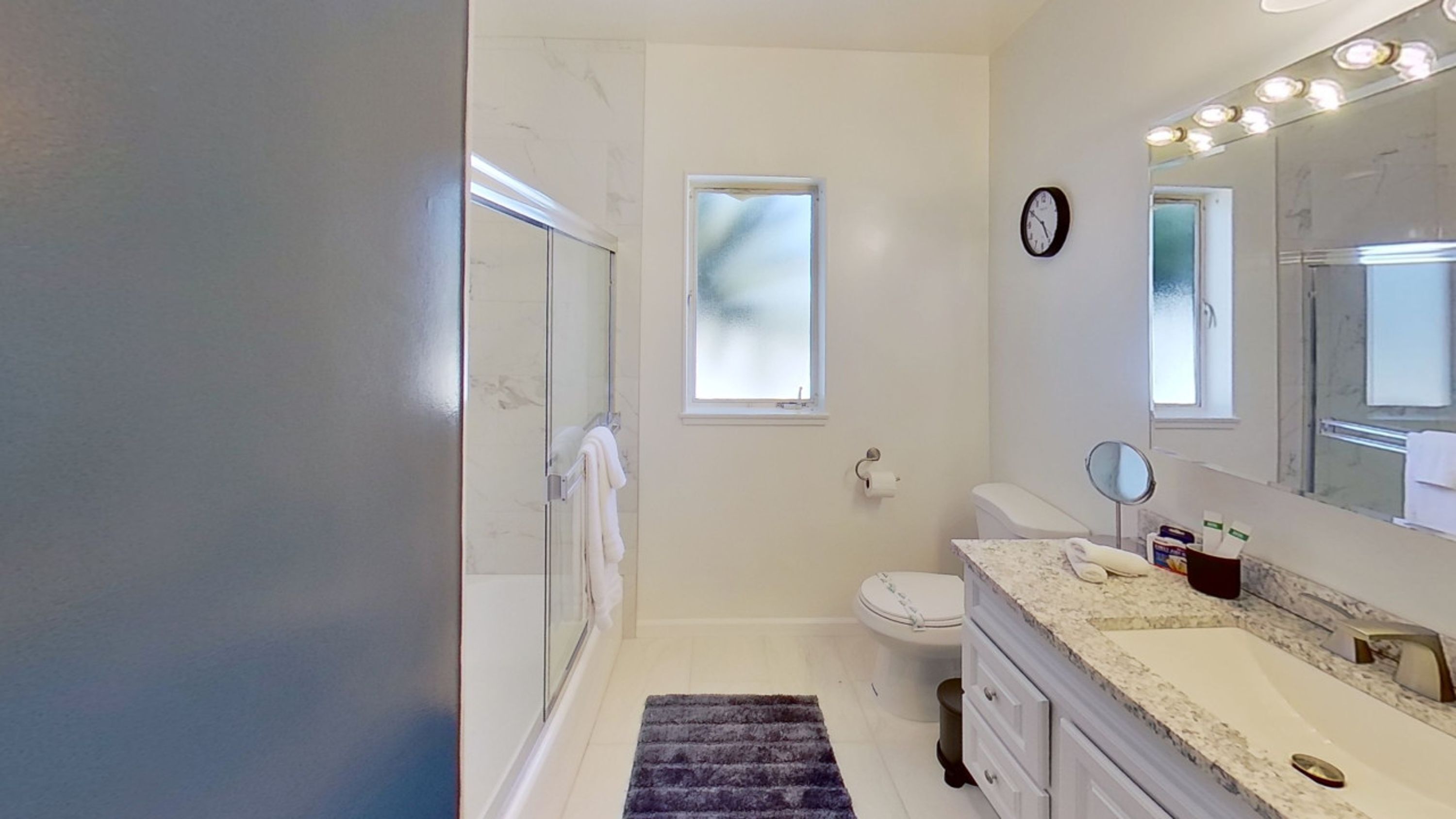 Une salle de bain avec une douche en verre, des toilettes, un lavabo avec un miroir et une fenêtre.