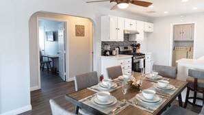 A modern kitchen with white cabinets, a built-in oven, and a dining area with a wooden table set for four.
