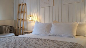 Een slaapkamer met een groot bed, een houten ladder, een wandlamp en twee ingelijste foto's.