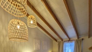 Een kamer met een bed, twee bedlampen, een rieten stoel, een klein tafeltje en een raam met gordijnen.