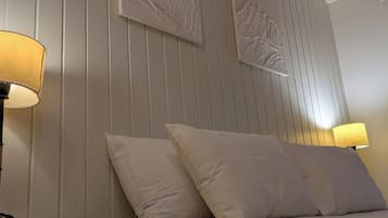 Een kamer met een bed, twee wandlampen en twee kunstwerken aan de muur.