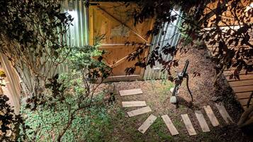 Een tuinpad dat leidt naar een houten poort, omringd door beplanting en een metalen hek.
