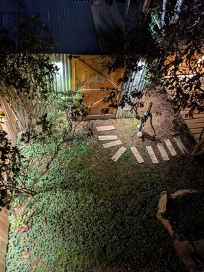 A garden pathway leading to a wooden gate, surrounded by foliage and a metal fence. - Los Calafates Hotel (Ushuaia)