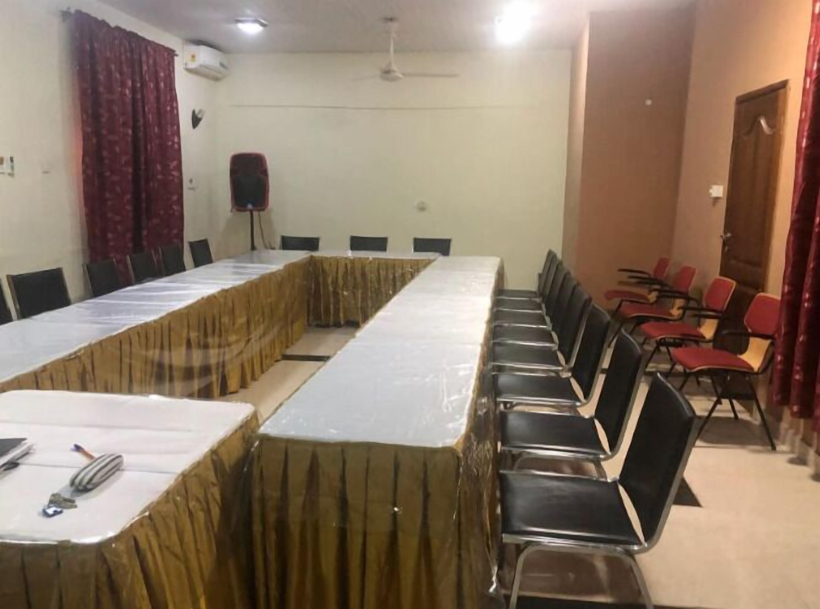 Une salle de conférence avec une longue table et des chaises, un podium et une porte.