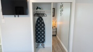 A compact room with a built-in ironing station, a small shelf with an iron, and a mirror above the door. - Disneyland 5BR Fullerton House Fully Remodeled 2023 w Garage Fenced Yard p61 (Fullerton)