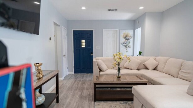 A modern living room with a beige sofa, a coffee table, and a blue door in the background. - Disneyland 5BR Fullerton House Fully Remodeled 2023 w Garage Fenced Yard p61 (Fullerton)