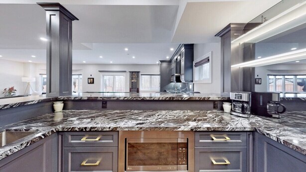 A modern kitchen with a marble countertop, built-in microwave, and dark cabinetry. - Family Modern Walkout Basement w Sauna Ski Resort 30min (Innisfil)