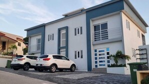 A modern two-story building with a flat roof, large windows, and a balcony.