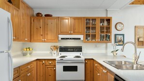 Une cuisine avec des meubles de rangement en bois, une cuisinière blanche et un évier.