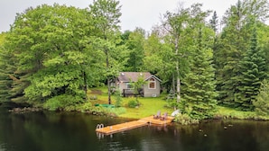 Une cabane au bord d’un lac, entourée d’une forêt dense.
