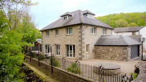 A stone house with a sloped roof, a small porch, and a stone wall.