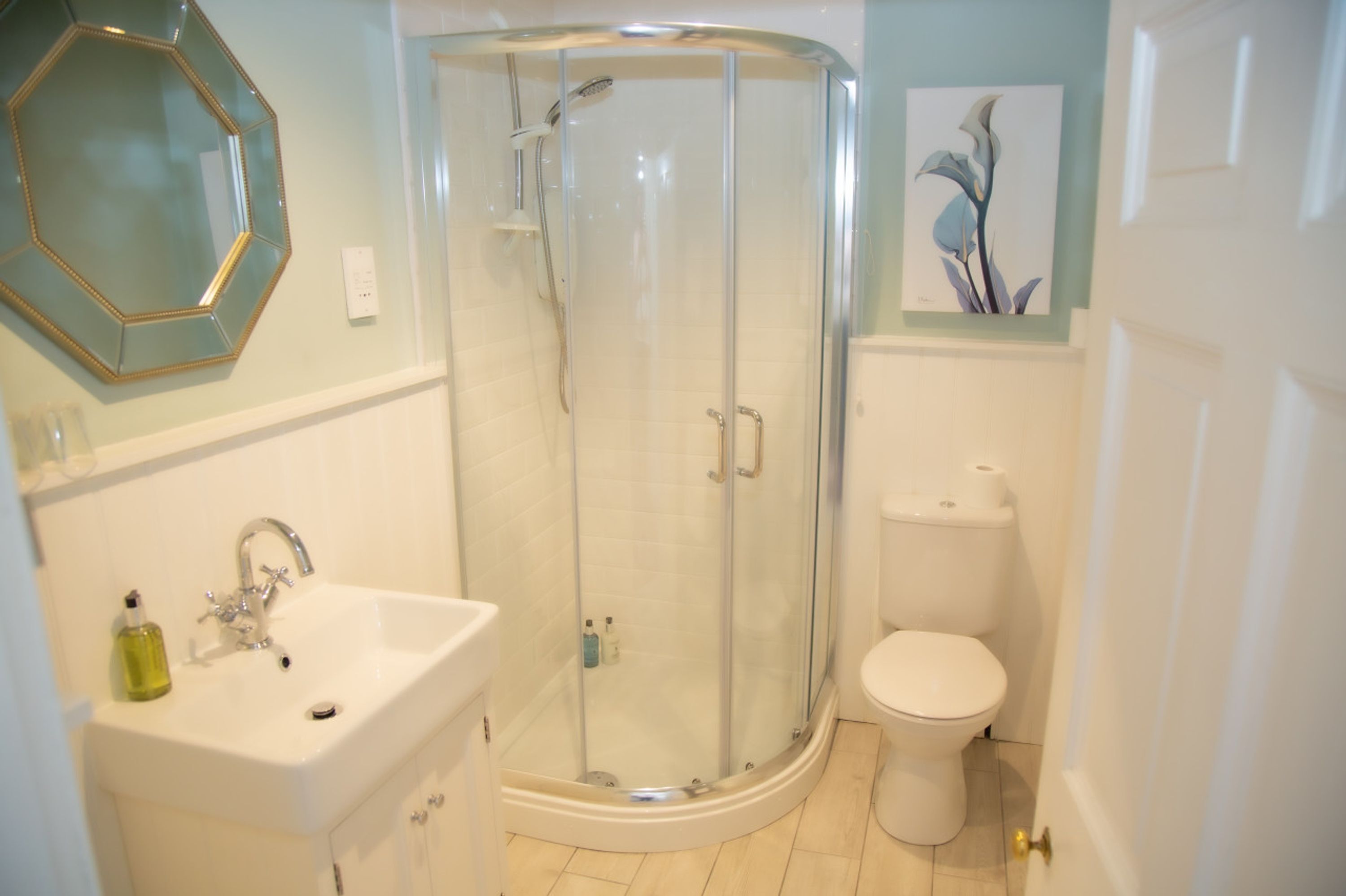 Un bany amb dutxa tancada per vidre, un lavabo blanc i un vàter.