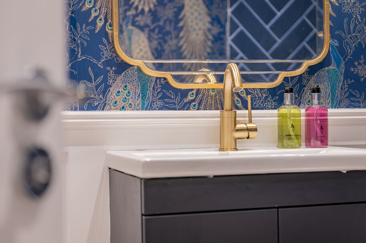 A bathroom with a gold faucet, a white sink, and two bottles of Coleslaw.