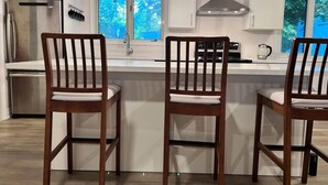 A modern kitchen with white cabinets, a stainless steel refrigerator, a double sink, and two wooden bar stools. - Marmora Hideaway - Peaceful Cottage w Wi-fi Clearwater (Marmora and Lake)
