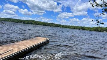 A wooden dock extending into a lake with a forested shoreline in the background.
