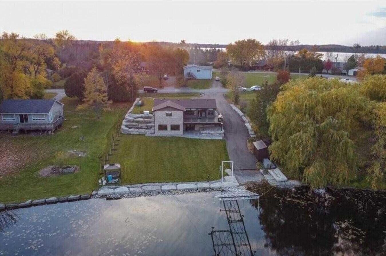 A residential area with a house, a small pond, and a bridge in the background.