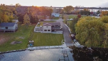 A residential area with a house, a small pond, and a bridge in the background.