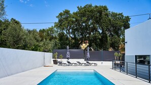 A rectangular swimming pool with clear blue water, surrounded by a white tiled deck. There are several lounge chairs and umbrellas arranged around the pool. - Casa do Moinho - V3 w/ Private Pool (Abrantes)