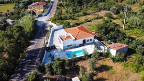 An aerial view of a residential property with a swimming pool, a detached garage, and a road leading to a yellow house. - Casa do Moinho - V3 w/ Private Pool (Abrantes)