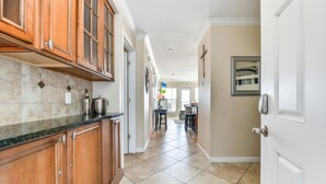 A kitchen with wooden cabinets, a black countertop, and a tiled floor. - Seascape 1108 in Galveston (Galveston)