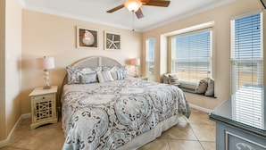 A bedroom with a bed, a nightstand, a ceiling fan, and a window with blinds. - Seascape 1108 in Galveston (Galveston)