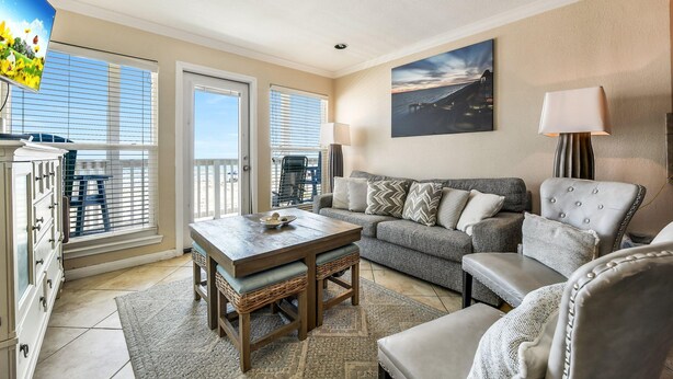 A living room with a sofa, armchairs, a coffee table, and a TV. There are windows with blinds, a lamp, and a painting on the wall. - Seascape 1108 in Galveston (Galveston)
