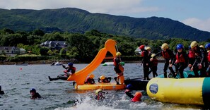 A water activity with inflatable slides and rafts, surrounded by a lake and hills. - Holiday Home With View of Kenmare Bay Estuary (Kenmare)