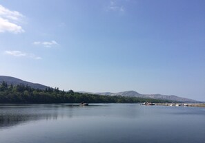 A calm lake with boats, surrounded by trees and mountains. - Holiday Home With View of Kenmare Bay Estuary (Kenmare)