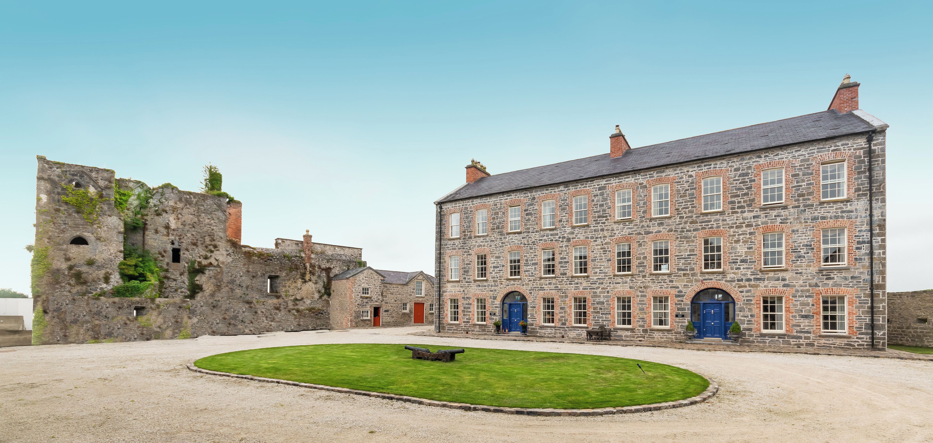 A historic stone building with a courtyard, featuring a mix of stone and brick construction, and a large blue door.