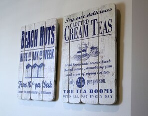 Two wooden signs advertising 'Beach Huts' and 'Cream Teas' with details about hiring and tea offerings.