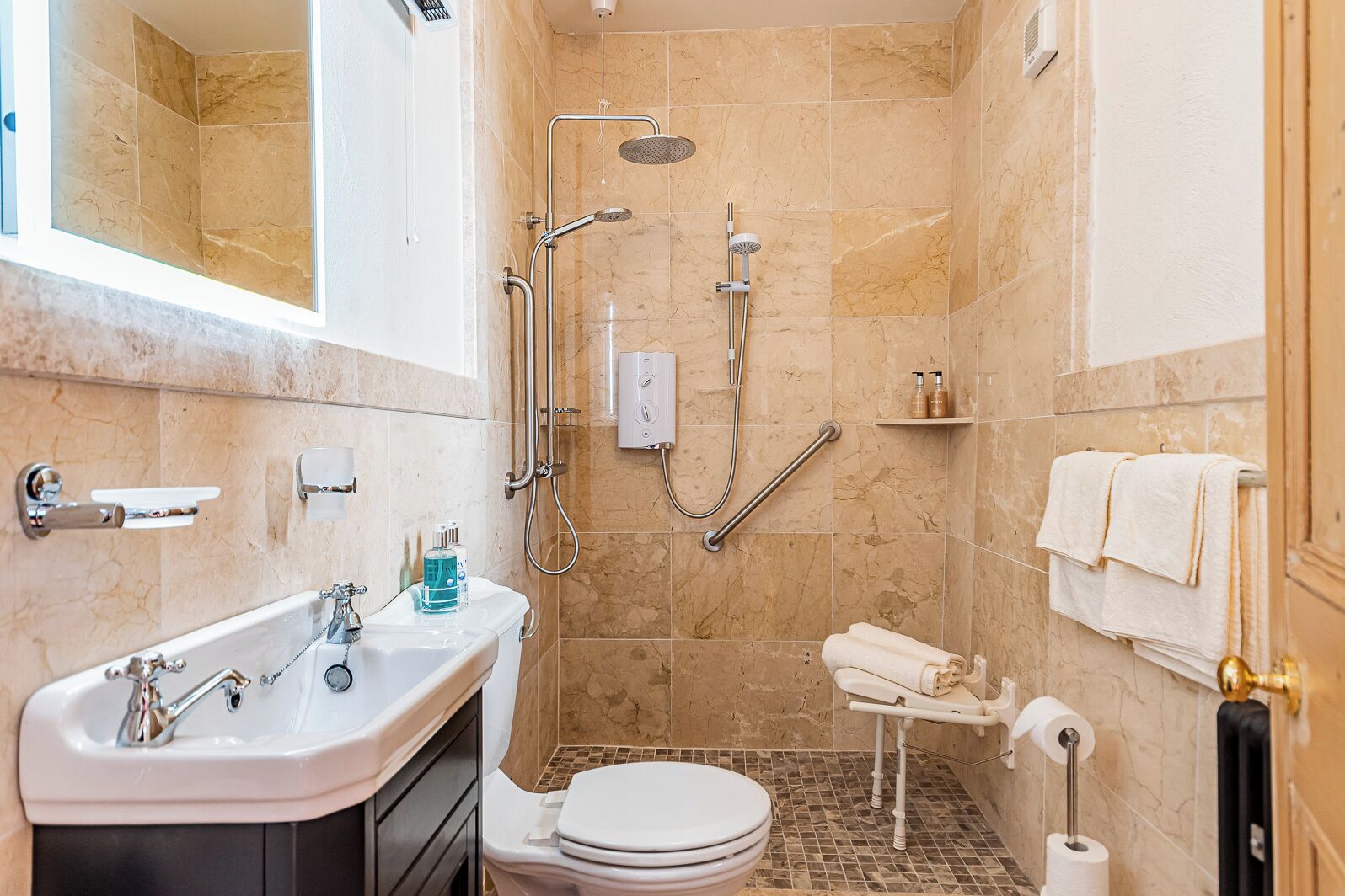 Un baño pequeño con ducha, inodoro, lavamanos y un perchero para toallas.