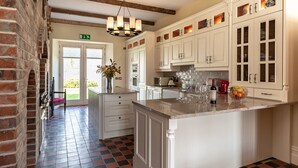 A kitchen with white cabinets, a central island, and a chandelier. - 8 Bedroomed House Steeped in History (Ennis)