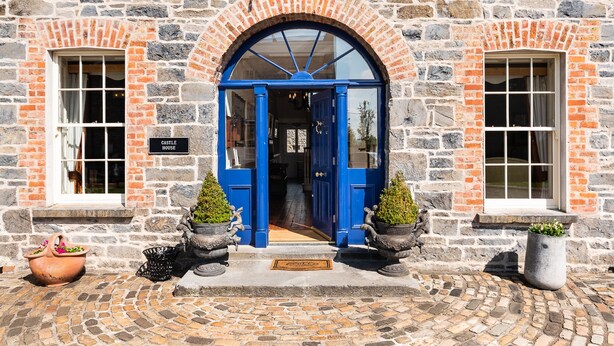 A stone building with a blue door, two windows, and potted plants. - 8 Bedroomed House Steeped in History (Ennis)