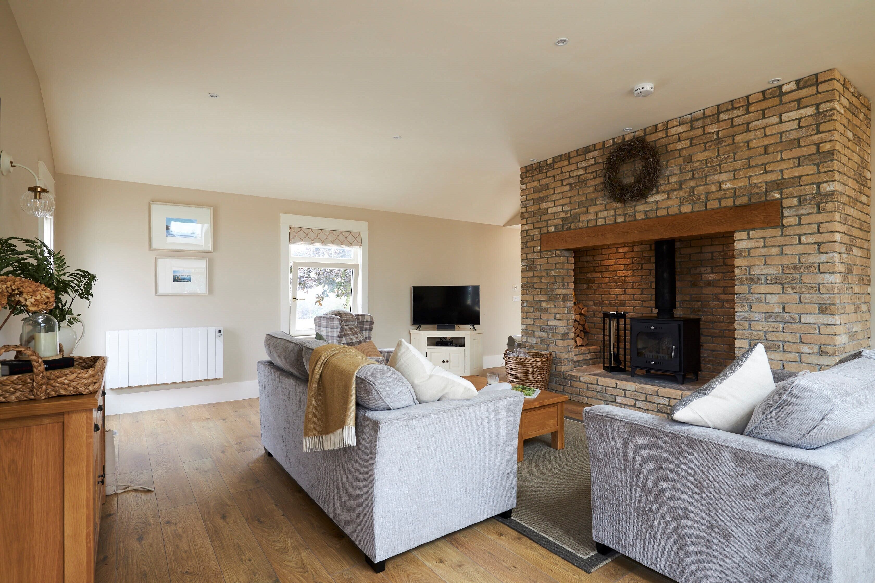 A living room with a fireplace, a sofa, a television, and a wooden cabinet.