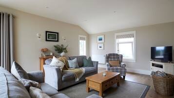 A living room with a sofa, armchair, coffee table, and television.