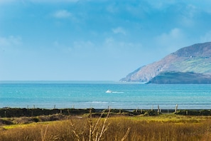 A coastal landscape with a body of water, a distant hill, and a fence in the foreground. - Family Beach House Located Within a Short Stroll of Waterville (Waterville)