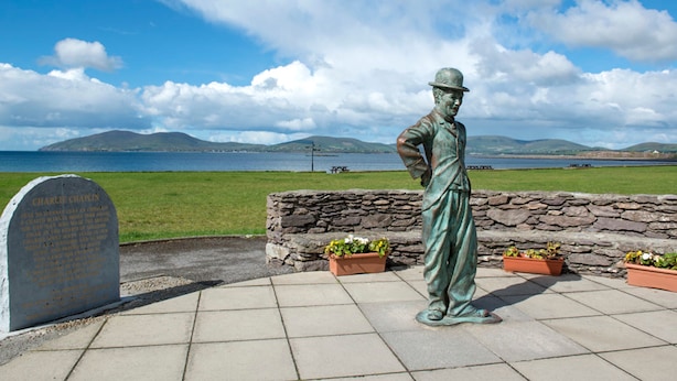 A statue of a man in a hat and coat, a headstone, and a stone wall with potted plants. - 4 Bedroomed House in Waterville Close to the Beach (Waterville)