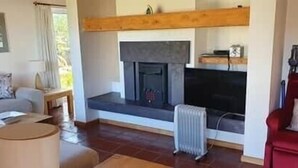 A living room with a fireplace, a red sofa, a grey sofa, and a coffee table. - 4 Bedroomed House in Waterville Close to the Beach (Waterville)