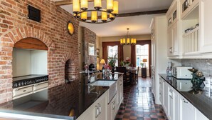 A kitchen with a brick wall, a large island, and white cabinetry. - Beautifully Restored Soldier s Barracks to Sleep 10 People (Ennis)