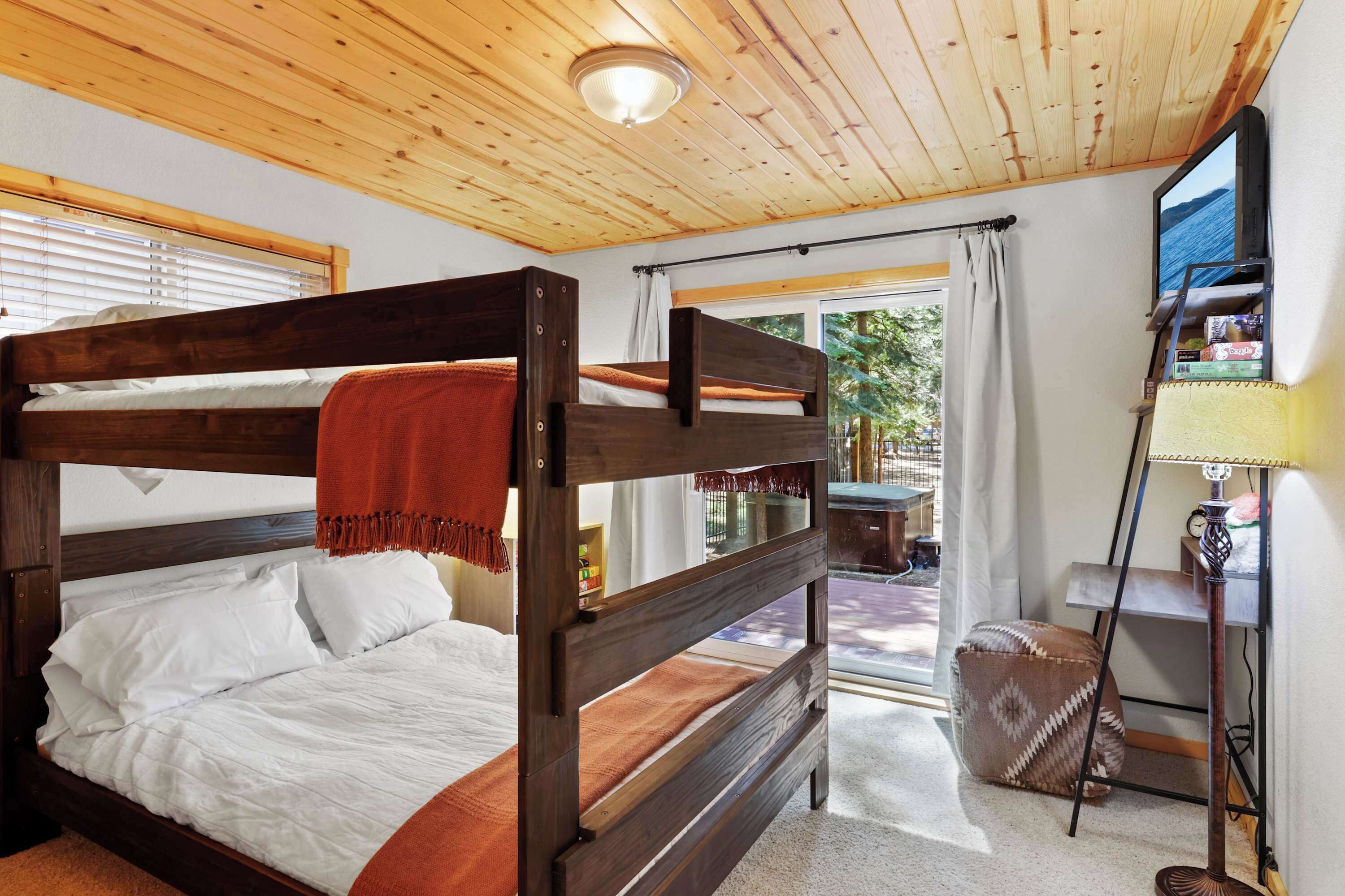 Uma cama de beliche com cabeceira de madeira e uma mesinha com abajur.