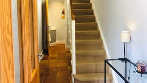 A staircase with carpeted steps, a handrail, and a glass railing with a candle holder.