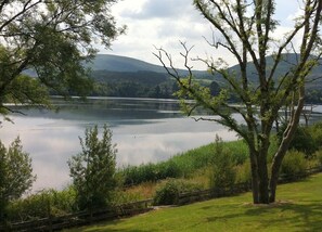 A tranquil lakeside view with a stone wall and a tree in the foreground. - 3 Bedroomed House With View of Kenmare Bay Estuary (Kenmare)