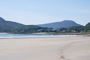 Une plage avec une montagne en arrière-plan et des maisons sur le versant de la colline.