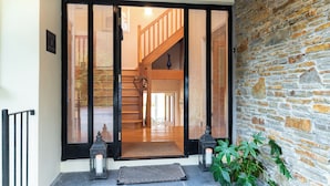 A wooden staircase leading to an upper floor, a stone wall, and a door with a black frame. - A Split-level Spacious Home With sea Mountain Views (Greenane)