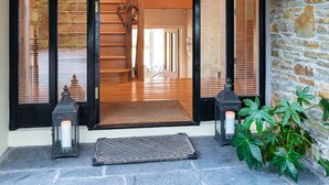 A wooden staircase leading to an upper level, a stone wall, and a door with a black frame. - A Split-level Spacious Home With sea Mountain Views (Greenane)