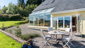 A house with a conservatory, stone patio, and outdoor seating area. - A Split-level Spacious Home With sea Mountain Views (Greenane)
